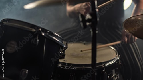 Enthusiastic female drummer plays a drum kit holding drumstick photo