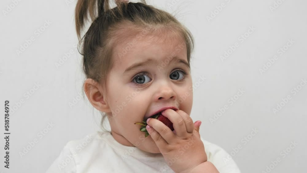 Close-up of the face of a child eating strawberries. High quality. Cute little girl. Close-up of the face of a child eating strawberries. High quality. Cute little girl.