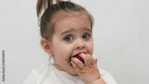 Close-up of the face of a child eating strawberries. High quality. Cute little girl.