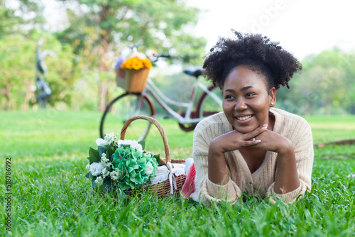 A beautiful woman of African descent wearing a yellow shirt. Relax and read in the park.