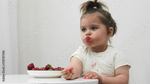 Funny little girl is trying to get up after eating strawberries. Funny moment.