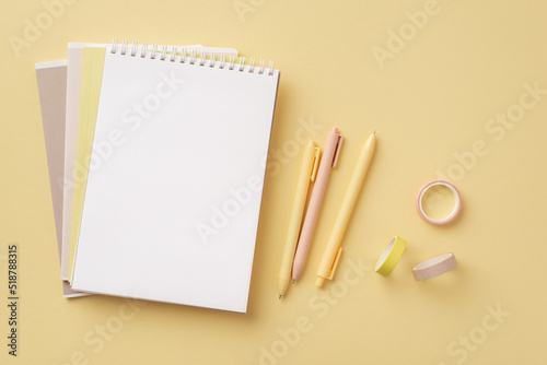 School supplies concept. Top view photo of stationery copybooks adhesive tape and pens on isolated pastel yellow background with empty space