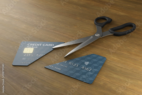 Bild auf Leinwand Scissors cut a credit card into halves on a wooden table