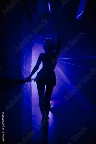 Silhouette stylish show woman in stage costume on stage in night club party at dark neon background