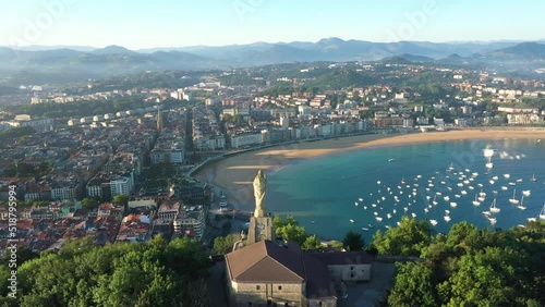 Unique cinematic perspective of the European city SAN SEBASTIAN. Situated in Spain -Vesque Country. Famous travel destination. Drone rotating around the Statue of Jesus. Panoramic view of the old city