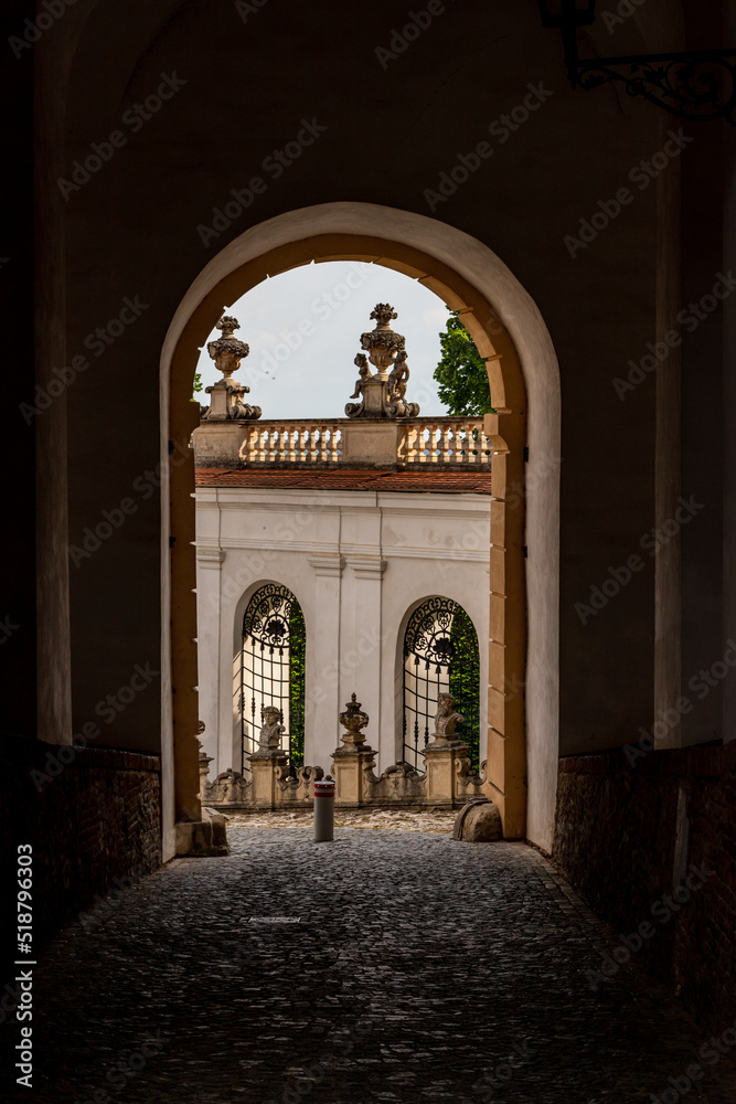 Vertical photo of view through arch to medieval town Mikulov, Czech Republic, Europe. Medieval sculptures, wall and windows at the end of dark archway with cobble road.
