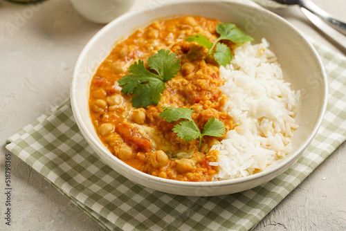 Indian red lentil curry with chickpeas, white rice and fresh cilantro - chana dal - in a white bowl on a green checkered kitchen towel