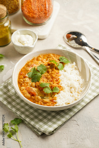 Indian red lentil curry with chickpeas, white rice and fresh cilantro - chana dal - in a white bowl on a green checkered kitchen towel photo
