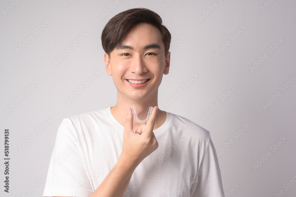 Young smiling man holding invisalign braces over white background studio, dental healthcare and Orthodontic concept.. Young smiling man holding invisalign braces over white background studio, dental healthcare and Orthodontic concept..