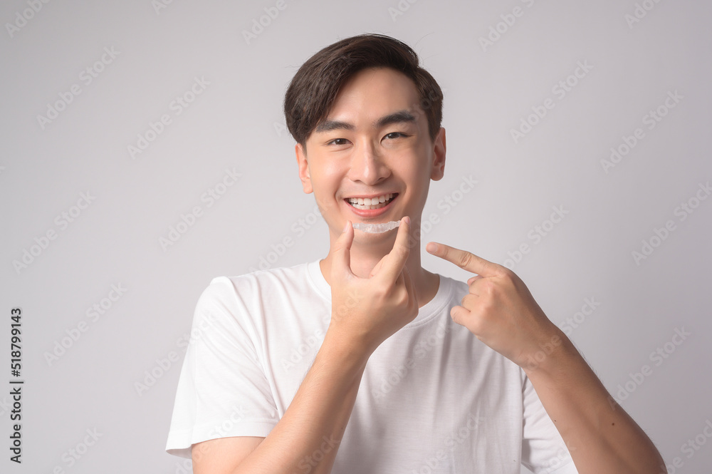 Young smiling man holding invisalign braces over white background studio, dental healthcare and Orthodontic concept.. Young smiling man holding invisalign braces over white background studio, dental healthcare and Orthodontic concept..