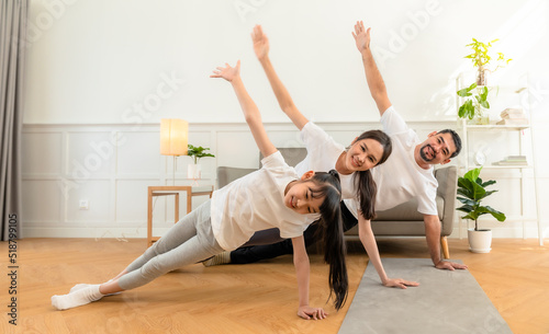 Young asian parents with child meditating at home isolated in room. Family, sport, yoga concept.