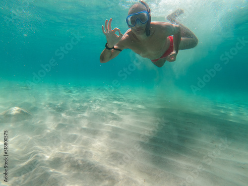 underwater man showing ok signin the sea with crystal-clear waters of the island of Mallorca. Concept of holiday relax summer beach diver in the sea 