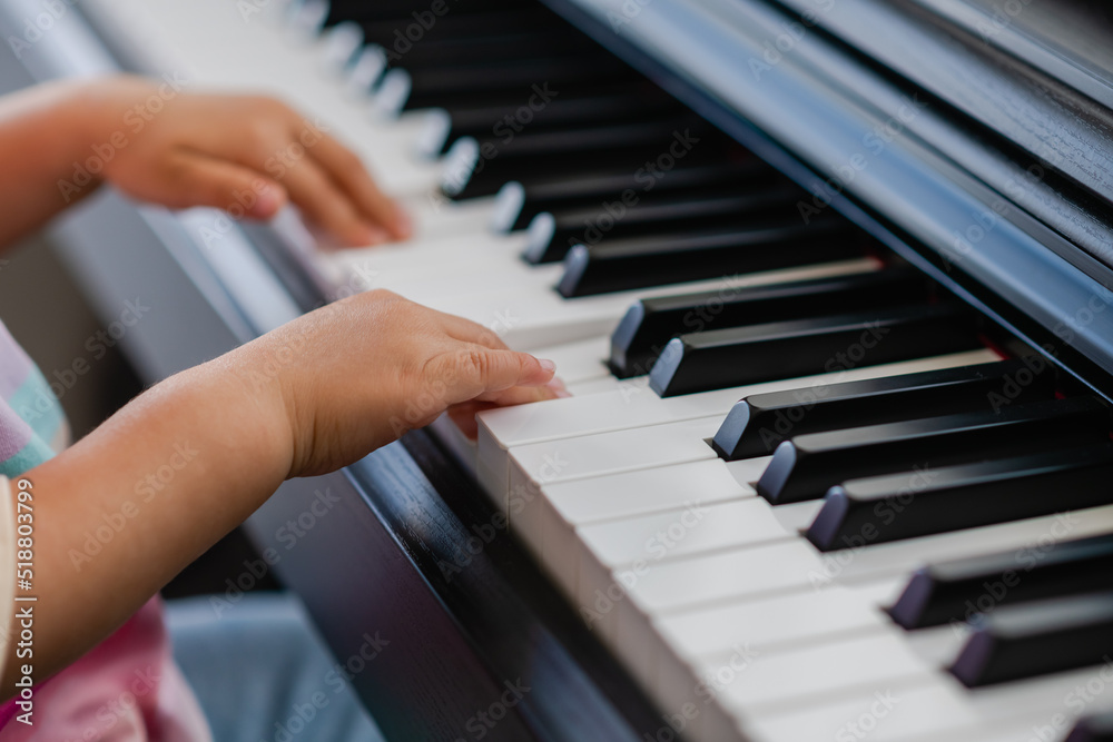 Hands of little girl playing piano, selective focus Hands of little girl playing piano, selective focus
