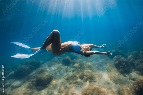 Woman freediver in bikini glides with fins. Freediving and beautiful sunlight in ocean