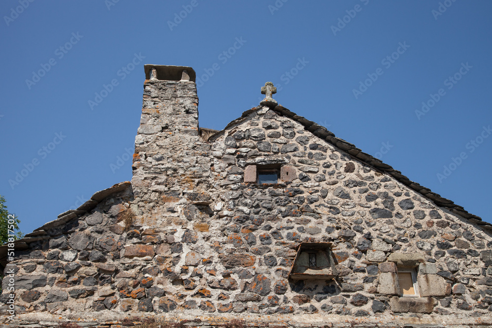 Pignon surmonté d'une croix et de sa cheminée dans le village de Fay sur Lignon en Haute-Loire