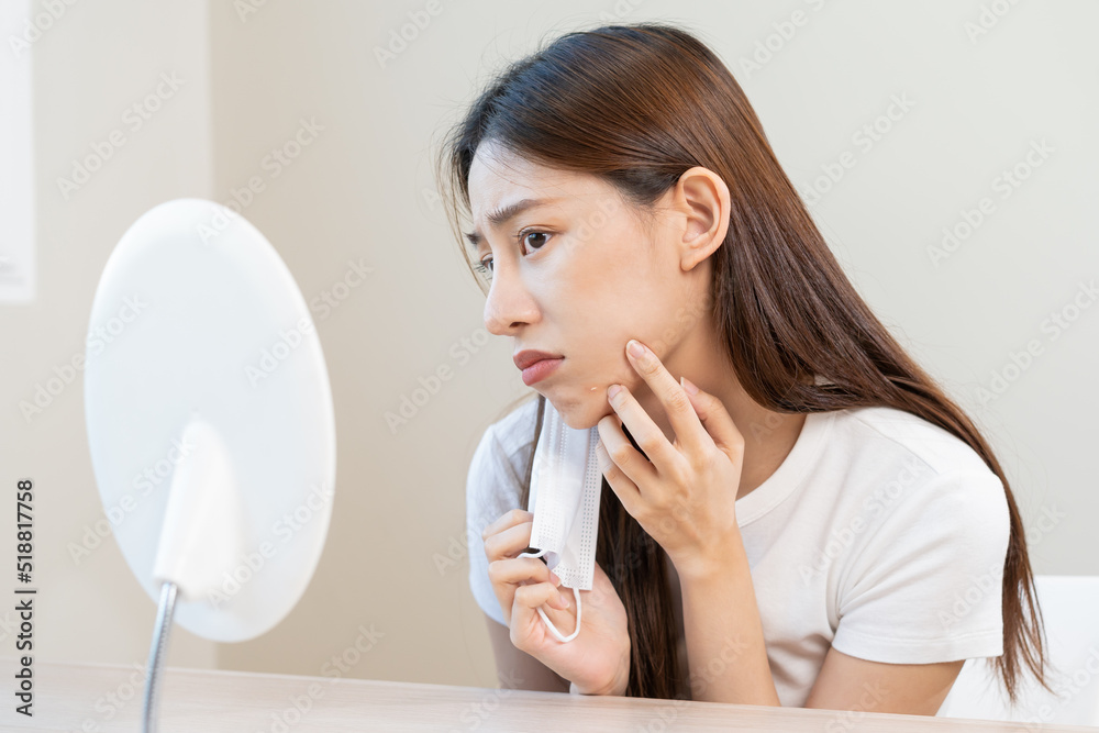 Dermatology, puberty asian young woman, girl looking into mirror, allergy when wear mask and cosmetic, show squeezing pimple spot for removing from face.Beauty care from skin problem by acne treatment Dermatology, puberty asian young woman, girl looking into mirror, allergy when wear mask and cosmetic, show squeezing pimple spot for removing from face.Beauty care from skin problem by acne treatment