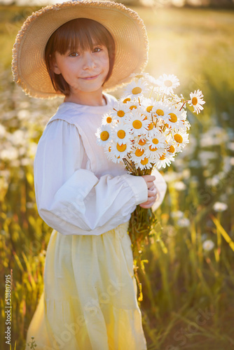 cute little girl with a bouquet of daisies on a sunny flowers meadow