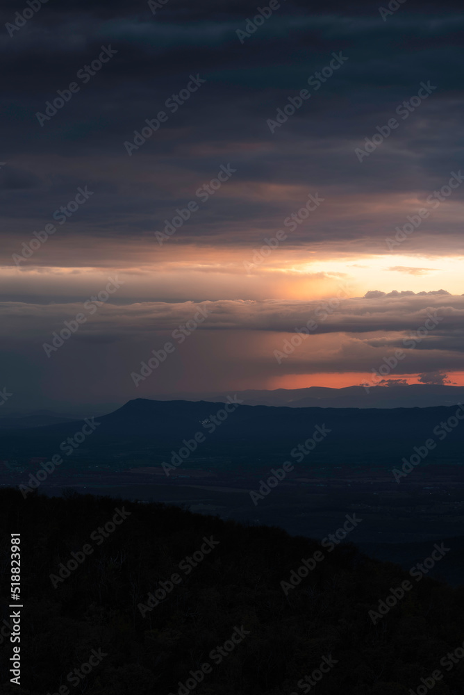 Dramatic sunset light illuminates distant downpours across the Shenandoah Valley and behind Massanutten Mountain.