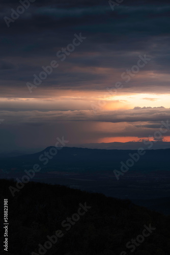 Dramatic sunset light illuminates distant downpours across the Shenandoah Valley and behind Massanutten Mountain.