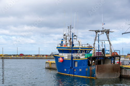 A blue fishing boat sits idle in Bonavista Harbour, Newfoundland, on a gloomy and overcast day.