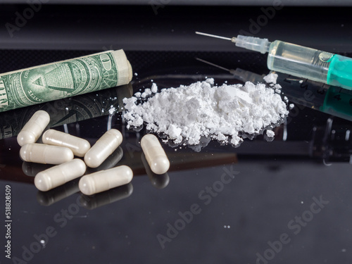 Money and drugs on a black glass table.