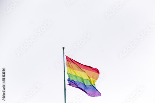 Close Up rainbow gay pride flag outside on a street. Symbol of the Lesbian Bisexual Transgender LGBT community waving in wind against cloudy sky. Social movement for freedom and equliaty. Copy Space © Defree