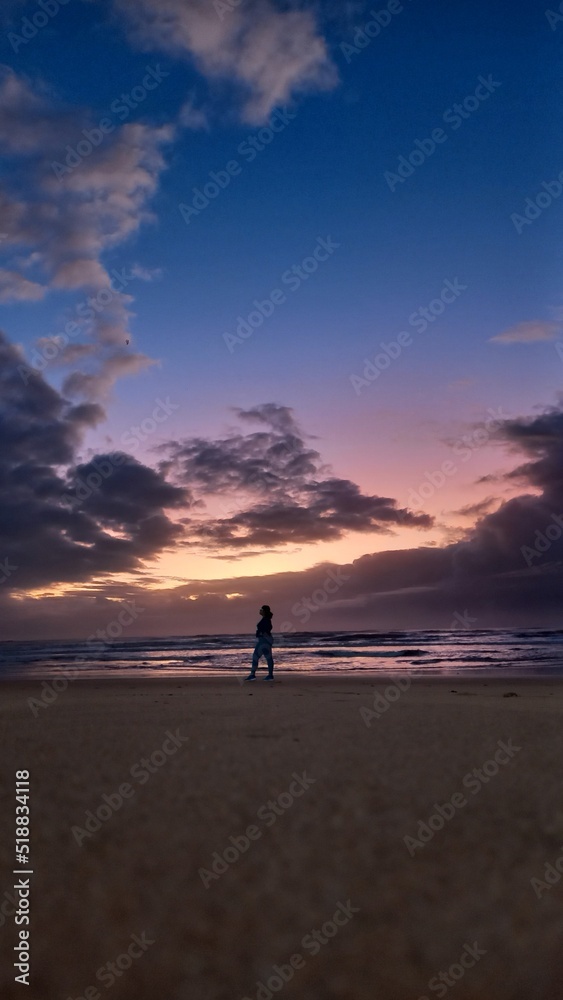 Landscape showing Woman silhouette in dramatic and colorful sunrise in the background at Jacaraipe Serra Espirito Santo beach