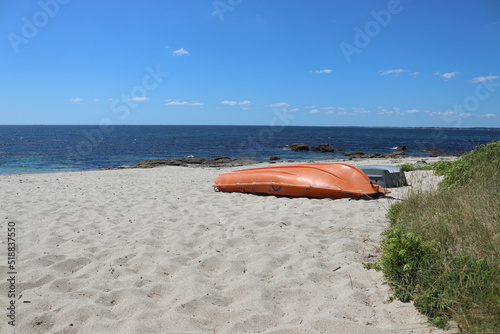 orange boat on the sand at the beach with the sea in the background