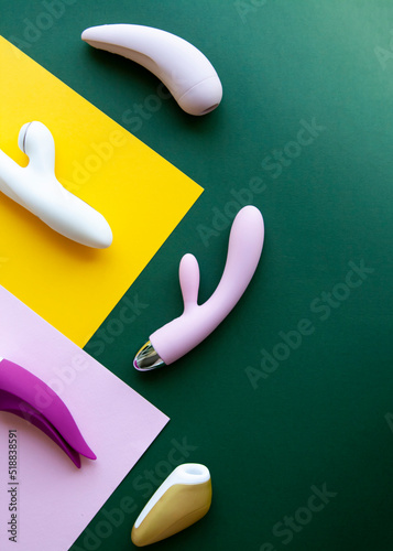 Collection of different types of sex toys on a pink, green and yellow background. 