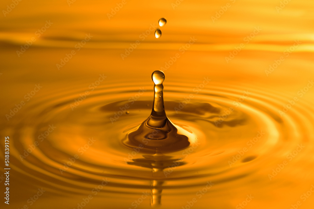 Splash of golden oily liquid with drops as background, closeup Splash of golden oily liquid with drops as background, closeup