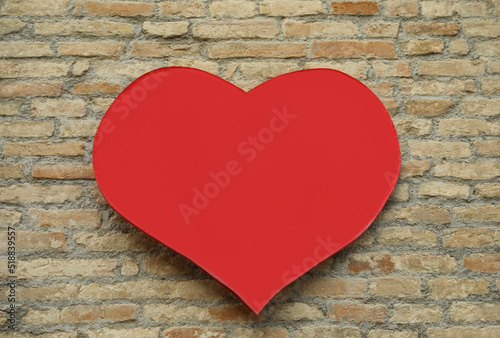 Empty heart shaped sign on brick wall. Space for design