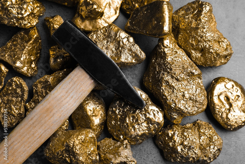 Gold nuggets and hammer on grey table, flat lay photo