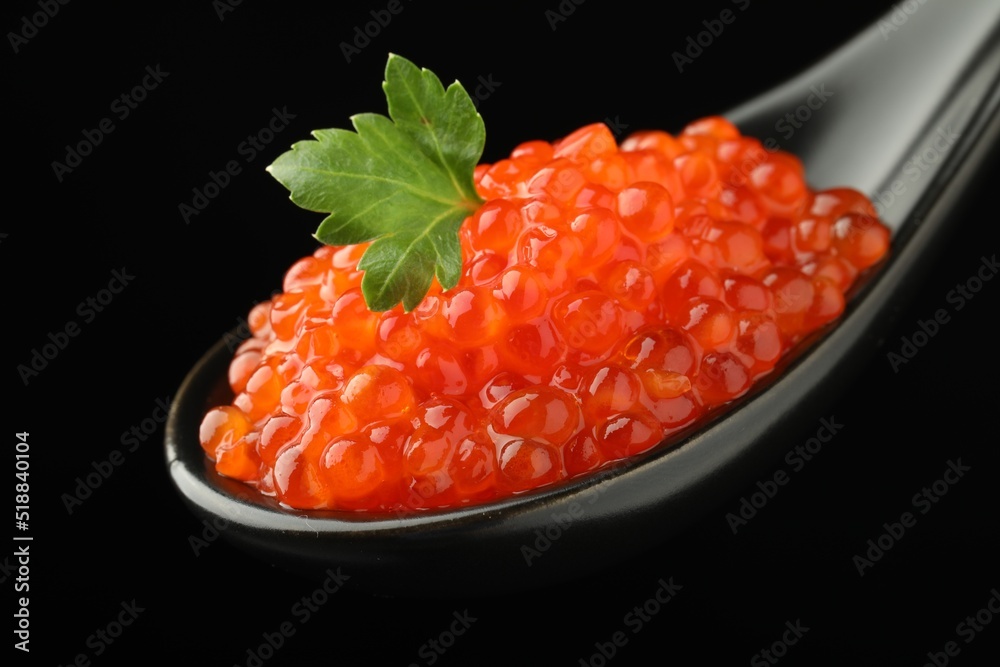 Spoon with delicious red caviar and parsley on black background, closeup Spoon with delicious red caviar and parsley on black background, closeup