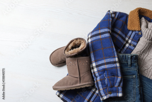 Warm child clothes and shoes on white wooden background, flat lay. Space for text photo