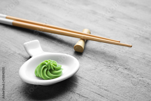 Plate with swirl of wasabi paste and chopsticks on grey table