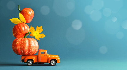 Retro truck with pumpkins and leaves on blue background. Concept of Thanksgiving day, Halloween and autumn postcards