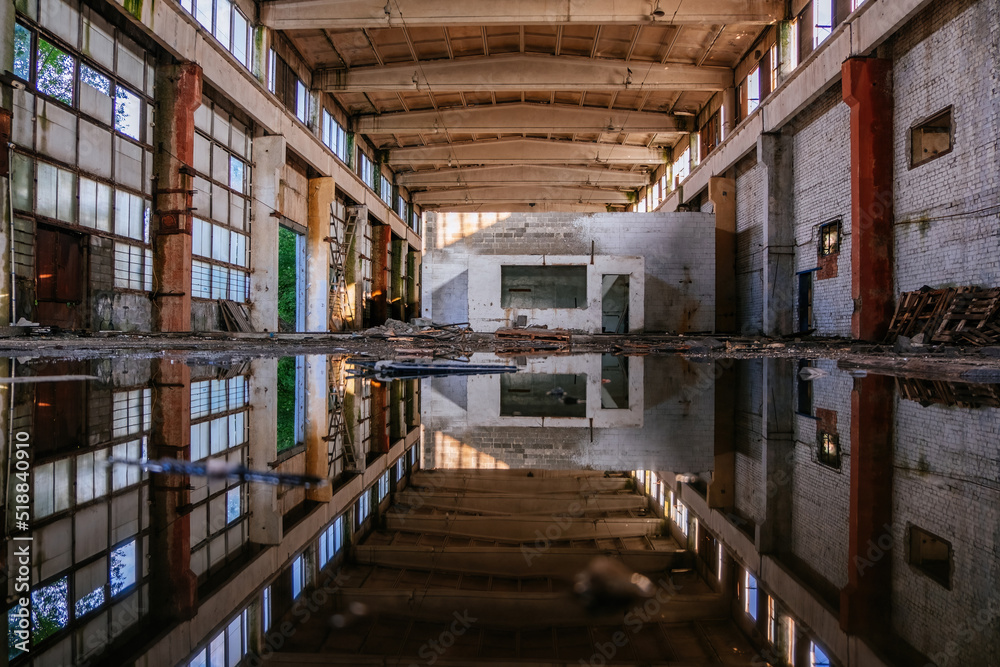 Inside of flooded dirty abandoned ruined industrial building with water reflection