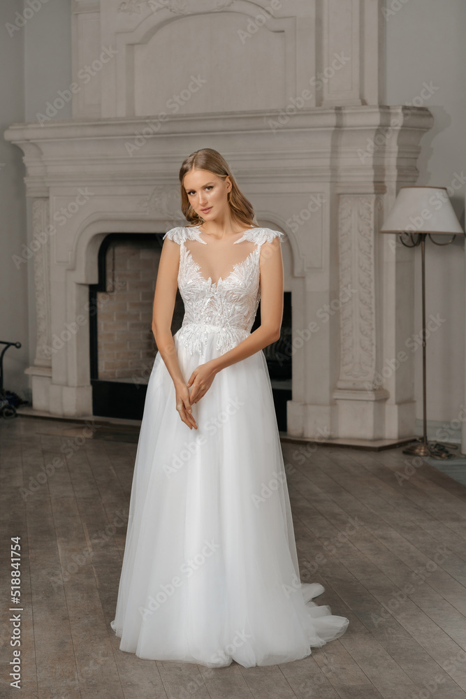 The beautiful woman posing in a wedding dress. Young beautiful happy bride wearing white wedding dress and posing in bright empty interior. Wedding fashion. Expensive Lace bust. The beautiful woman posing in a wedding dress. Young beautiful happy bride wearing white wedding dress and posing in bright empty interior. Wedding fashion. Expensive Lace bust.