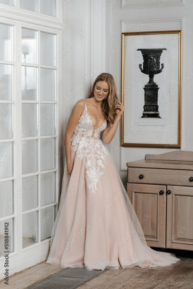 The beautiful woman posing in a wedding dress. Young beautiful happy bride wearing white wedding dress and posing in bright empty interior. Wedding fashion. Expensive Lace bust. The beautiful woman posing in a wedding dress. Young beautiful happy bride wearing white wedding dress and posing in bright empty interior. Wedding fashion. Expensive Lace bust.