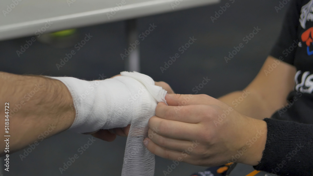 Professional fighter in the locker room puts bandage on the hand before fight. Professional fighter is prepared in the locker room before fight