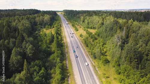 Aerial view of car driving through the forest on country road. Cip. Cars Driving Through Forest Road Drone Travel Countryside Adventure. Aerial view flying over old patched two lane forest road with