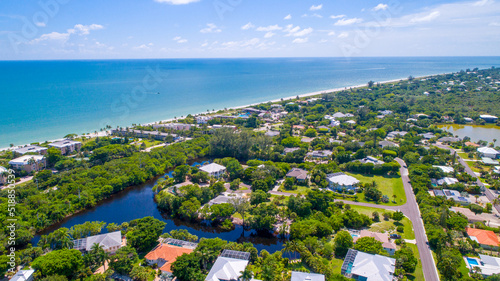 Sanibel, Florida Aerial Drone Perspective with Real Estate and Bay waters in the Foreground and Blue Water with a Beach in the Background © Ray Dukin