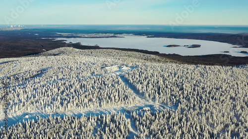 A beautiful aerial of people skiing in a snowy mountain at ski resort on blue sky background. Footage. Sunny, winter day in green pine trees forest and snowy Alps slopes with funicular. photo