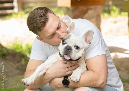 portrait of a young man with a french bulldog.young man plays teaches hugs kisses french bulldog