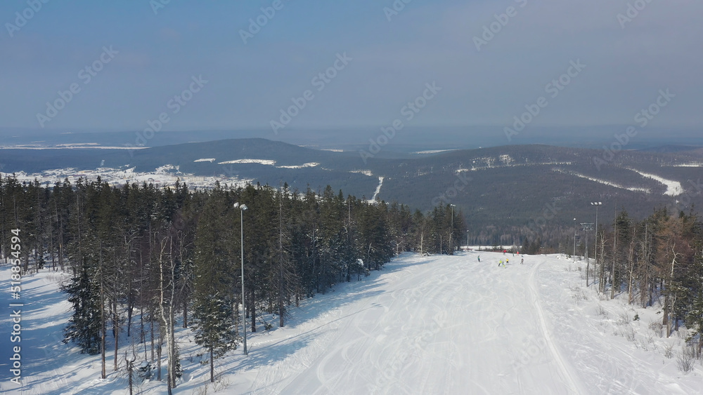 Panoramic view of sport resort for winter vacation, healthy lifestyle concept. Footage. People snowboarding and skiing down the hill on winter forest background.