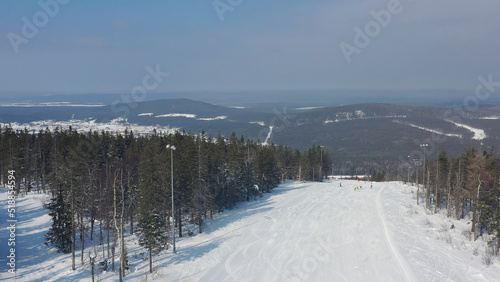 Panoramic view of sport resort for winter vacation, healthy lifestyle concept. Footage. People snowboarding and skiing down the hill on winter forest background.