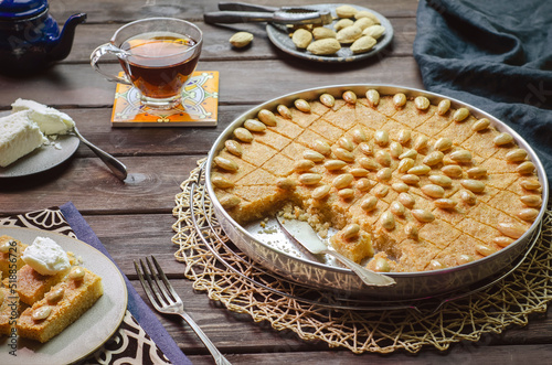 Arabic cuisine; Traditional Arabic dessert "Basbousa" .Egyptian oriental semolina cake topped with golden crispy almond. Served with tea and honey syrup.