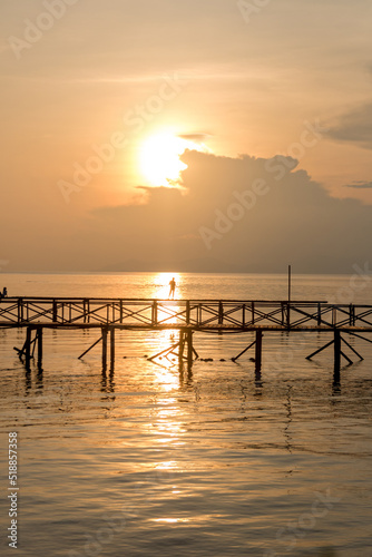 Silhouette of man fishing on jetty on mabul island in borneo photo