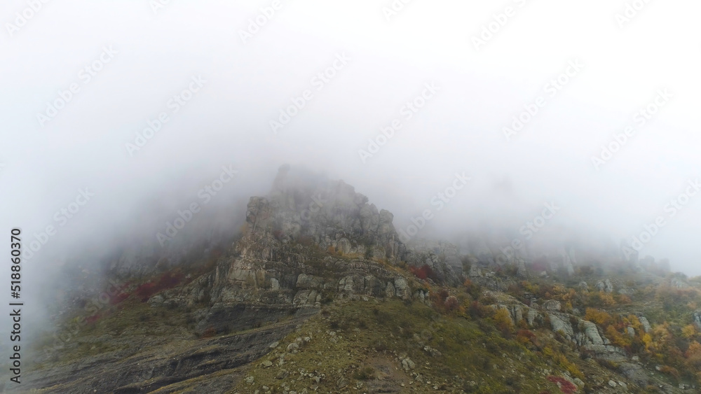 Aerial view on rocky mountains in the fog. Shot. Beautiful foggy mountains background. Mountain peak in the mist