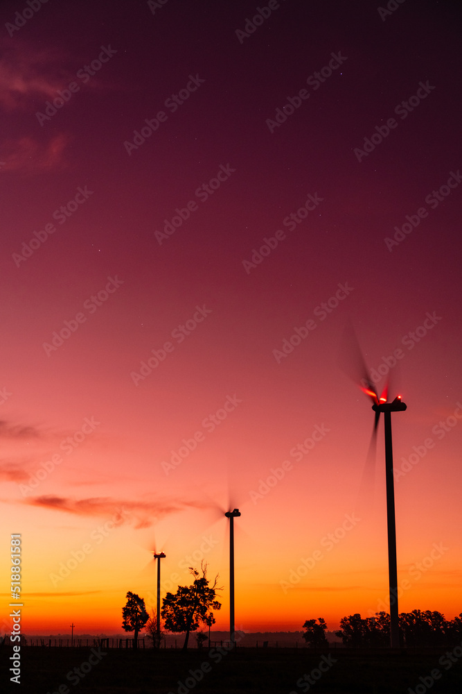 Silhouette of three modern windmills in a reddish sunset on the outskirts of Kiyú, San José, Uruguay